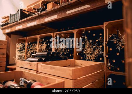 Bottiglie di vino immagazzinate in cassette di legno e contenitori di vino Foto Stock