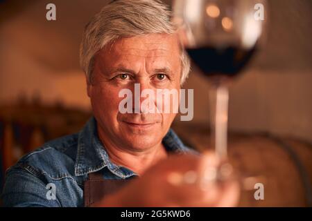Bell'uomo che tiene un bicchiere di vino rosso Foto Stock