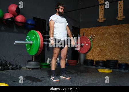 Giovane uomo barbuto che fa deadlift esercizio in una palestra crossfit. Foto Stock