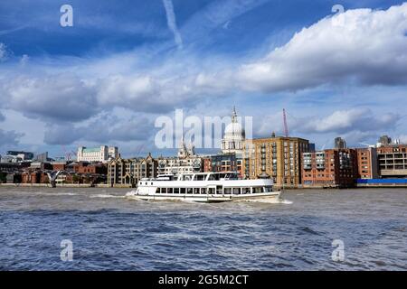 Barca da diporto che naviga lungo il Tamigi, Londra. Il Millennium Bridge e la Cattedrale di San Paolo sono visibili sullo sfondo. Giorno estivo con blu Foto Stock