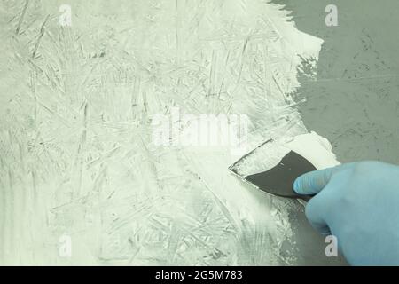 Cazzuola da costruzione sul tavolo durante il processo. Processo di ristrutturazione, sfondo con spazio per la copia. Coltello per stucco in un mastice sullo sfondo della parete Foto Stock