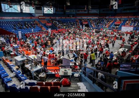 Gli operatori sanitari inoculano i pazienti con il vaccino COVID-19 Pfizer-BioNTech all'interno di uno stadio sportivo trasformato in un sito di vaccinazione temporanea a San Juan City, Metro Manila, Filippine. Foto Stock