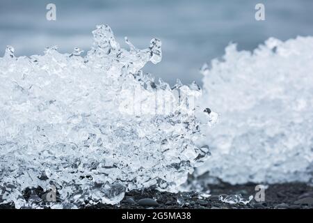 Un primo piano di pezzi di iceberg testurizzati che si fondono sulla sabbia nera a Diamond Beach, Islanda. Foto Stock