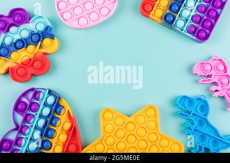 Set di popolari giocattoli di fidget colorati lo schioccano su sfondo blu. Nuovi giocattoli sensoriali anti-stress per bambini e adulti. Giocattoli a bolla di spinta alla moda. Copia spin Foto Stock