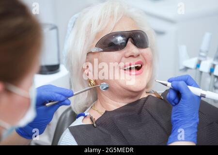 Donna anziana che indossa occhiali protettivi durante il trattamento dentale Foto Stock