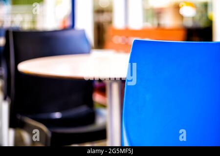 Tavolo vuoto all'esterno della caffetteria del ristorante con due colorate sedie blu sul marciapiede e sfondo bokeh con nessuno Foto Stock