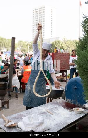 Tirare e piegare un filo di pasta sul mercato di Hotan Foto Stock