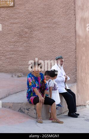 I nonni siedono con i loro due nipoti su un muro all'ombra Foto Stock