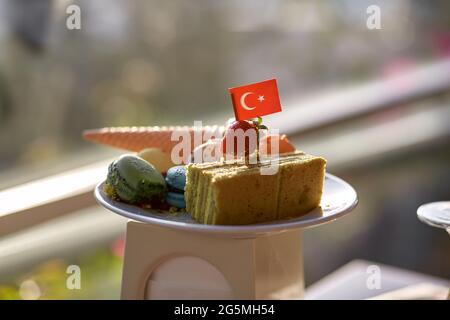 Torta sana di zucchine, gelato, macaroon e bandiera turca su un piatto bianco. La colazione in Turchia era deliziosa. Ampia selezione di deligh turchi Foto Stock