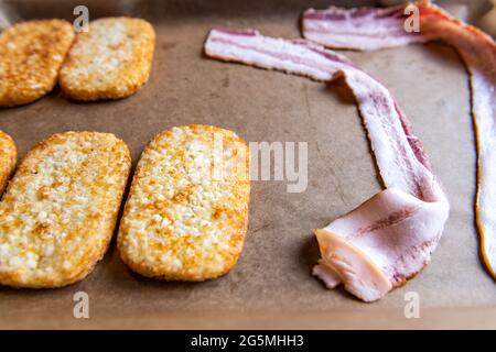 Macro closeup di teglia da forno con carta pergamena per patate fritte e strisce di pancetta crude non cotte Foto Stock