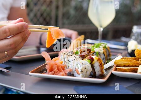 uomo che mangia sashimi di salmone in ristorante giapponese. Uomo che tiene i chopsticks che mangia sashimi di salmone fresco Foto Stock
