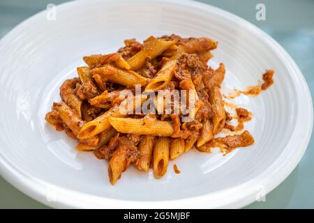 Chiocciole di marinara fresca di salsa di pomodoro rosso e agnello macinato o bolognese di carne di hamburger di manzo con pasta di penne noodle su fondo piatto bianco Foto Stock