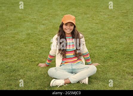 posa per foto. bella studentessa adolescente nel parco. bella sorridente sicuro studentessa rilassarsi sull'erba verde. felice infanzia. torna a scuola. Piccolo Foto Stock