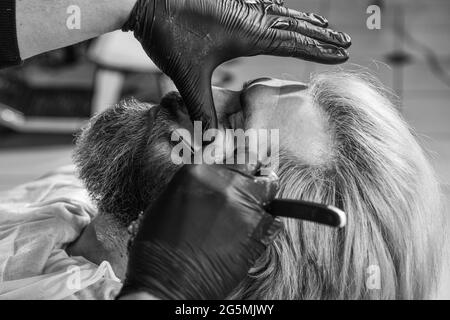 Ottimo tempo al barbiere. Uomo al parrucchiere. Barbiere professionale con cliente maschile. Hipster con barba e baffi. Uomo che vuole una nuova acconciatura Foto Stock