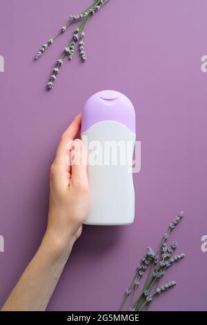 Bottiglia di shampoo femminile con base viola o lavanda. Cosmetici a base di erbe. Foto Stock