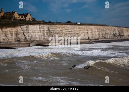 Piccole figure di surfisti vicino alla passeggiata sotto la scogliera di Brighton, Regno Unito Foto Stock