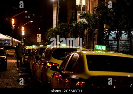 Sud America, Brasile: Coda di taxi sul lato del Teatro Municipale nel centro di Rio de Janeiro di notte. Cartelli per taxi illuminati. Cabine parcheggiate in fila. Foto Stock