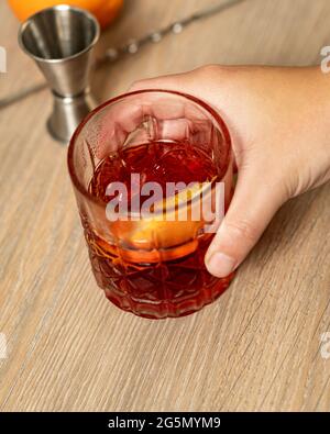 Vista panoramica del cocktail negroni sollevato con una mano Foto Stock