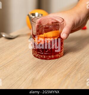 Vista panoramica del cocktail negroni sollevato con una mano Foto Stock