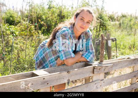Donna gioiosa che raccoglie le verdure in un cesto Foto Stock