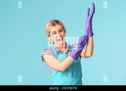 Giovane donna che indossa guanti su sfondo colorato Foto Stock