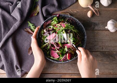 Donna che mangia gustoso couscous con verdure su sfondo di legno Foto Stock