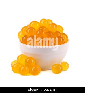 Perle di taperioca rosse per il tè delle bolle isolate su sfondo bianco. Perle di tapioca in cucchiaio bianco di ceramica. Foto Stock
