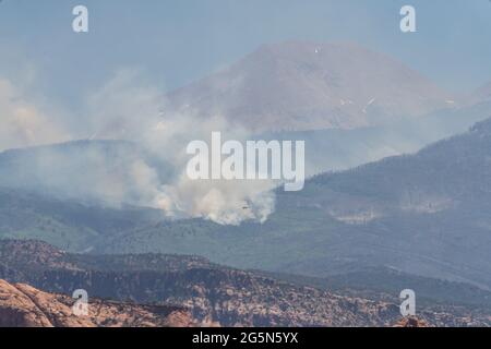 I pennacchi di fumo sorgono da un incendio nelle montagne la SAL dello Utah. Un elicottero antincendio vola per far cadere l'acqua sul fuoco. Foto Stock