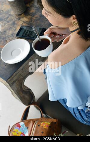 La donna asiatica gode di un caffe' mattutino in un cafe shop a Ubud, Bali, Indonesida Foto Stock