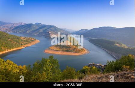 Paesaggio con un meandro di un fiume sullo sfondo di montagne e cielo blu con nuvole bianche Foto Stock