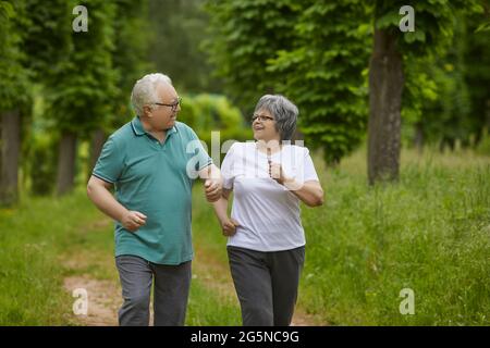 Felice gente anziana sana godendo un workout attivo di corsa in un parco estivo verde Foto Stock