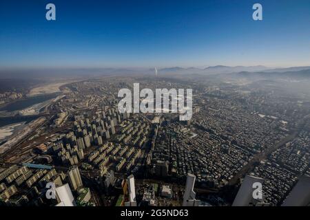 Scena diurna di Seoul, vista dalla cima della Lotte World Tower. La Lotte World Tower è un grattacielo alto 123 piani, 554.5 metri (1,819 piedi) che ha terminato la costruzione esterna il 17 marzo 2016. L'ultimo 123° piano dell'edificio è stato completato il 22 dicembre 2015. E' attualmente l'edificio piu' alto dell'OCSE ed e' il quinto edificio piu' alto del mondo. Foto Stock