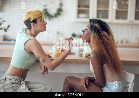 Donna attenta che allatta la fidanzata flirtatiosa di pelle scura Foto Stock