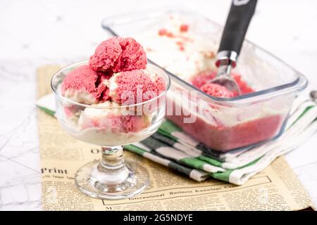 Yogurt gelato alla fragola in una ciotola di vetro, palline di gelato, contenitore con sundae fatto in casa Foto Stock