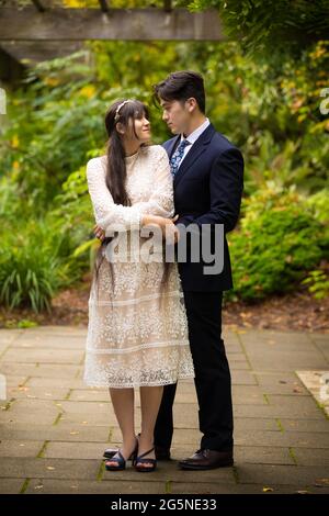 Sposa biraciale e sposo all'aperto in posa sotto pergola ricoperta di vite Foto Stock