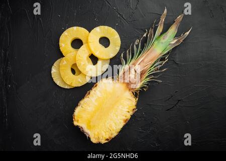 Set di ananas a fette, su sfondo nero scuro tavolo in pietra, vista dall'alto piatto Foto Stock