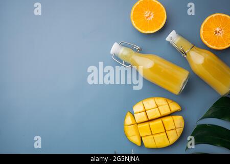 Frutta tropicale, ananas, mango e arance, su sfondo estivo testurizzato blu, vista dall'alto piatto, con spazio per la copia del testo Foto Stock