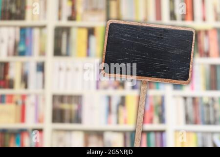 Etichetta lavagna vuota e libreria sfocata sullo sfondo. Risorse grafiche Foto Stock