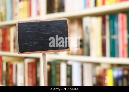 Etichetta lavagna vuota e libreria sfocata sullo sfondo. Risorse grafiche Foto Stock