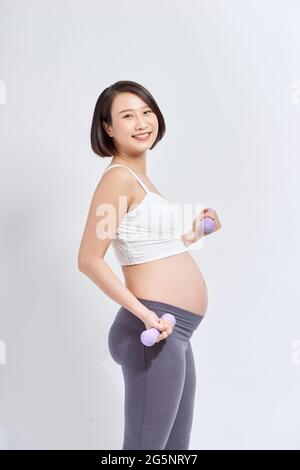Donna incinta asiatica fare esercizio, in piedi e sollevando dumbbells, concetto di maternità di gravidanza sportiva Foto Stock