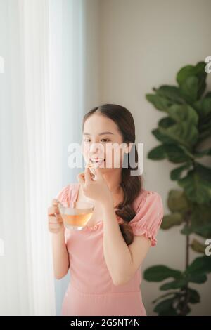 Belle Donne asiatiche mangiare nutrizionali dell'olio di pesce supplemento per la dieta sana a casa Foto Stock