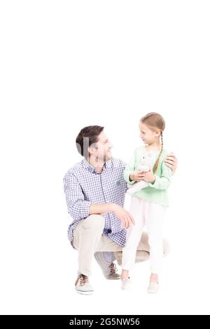 Verticale isolato studio ritratto di uomo caucasico maturo e sua figlia indossando abiti casual passare il tempo insieme, ragazza che tiene il giocattolo Foto Stock