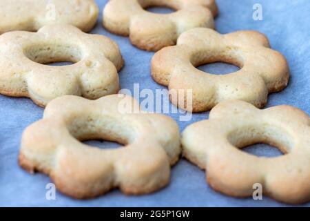 Biscotti shortbread cotti al forno sotto forma di fiori su una teglia da forno con carta pergamena appena tolta dal forno. Spuntino a base di tè per colazione. Selettivo Foto Stock