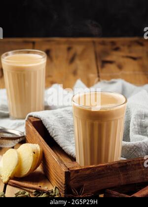 Due vetri sfaccettati su un tavolo di legno con la tradizionale bevanda indiana masala chai. Spazio di copia. Foto Stock