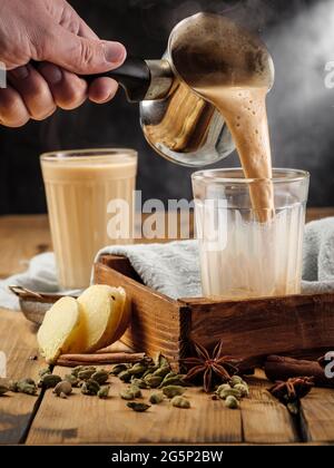 Due vetri sfaccettati su un tavolo di legno con la tradizionale bevanda indiana masala chai. Spazio di copia. Foto Stock