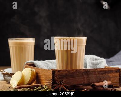 Due vetri sfaccettati su un tavolo di legno con la tradizionale bevanda indiana masala chai. Spazio di copia. Foto Stock