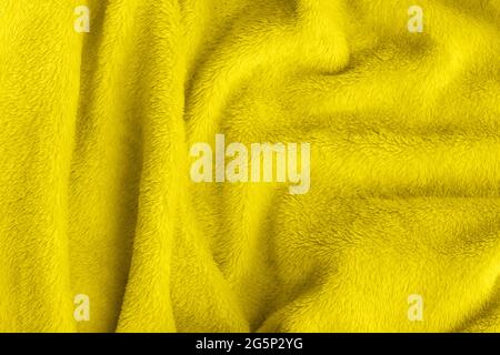 Tessuto morbido giallo illuminante. Tessuto crumpled faux fur coperta sfondo. Tendenza colore dell'anno 2021. Foto Stock