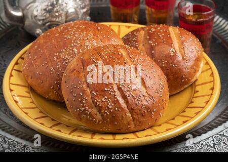 Coppia di tradizionali krachel marocchini appena sfornati, dolci panini, su un piatto da vicino servito con tè Foto Stock