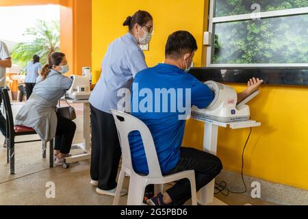 La gente ottiene il loro controllo di pressione sanguigna prima di ottenere i loro vaccini COVID-19 ad un centro di salute in Thailandia Foto Stock