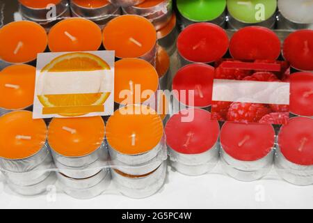 Candele di paraffina giacenti sullo scaffale del negozio. Varietà di candele di aroma giallo e rosso. Foto Stock